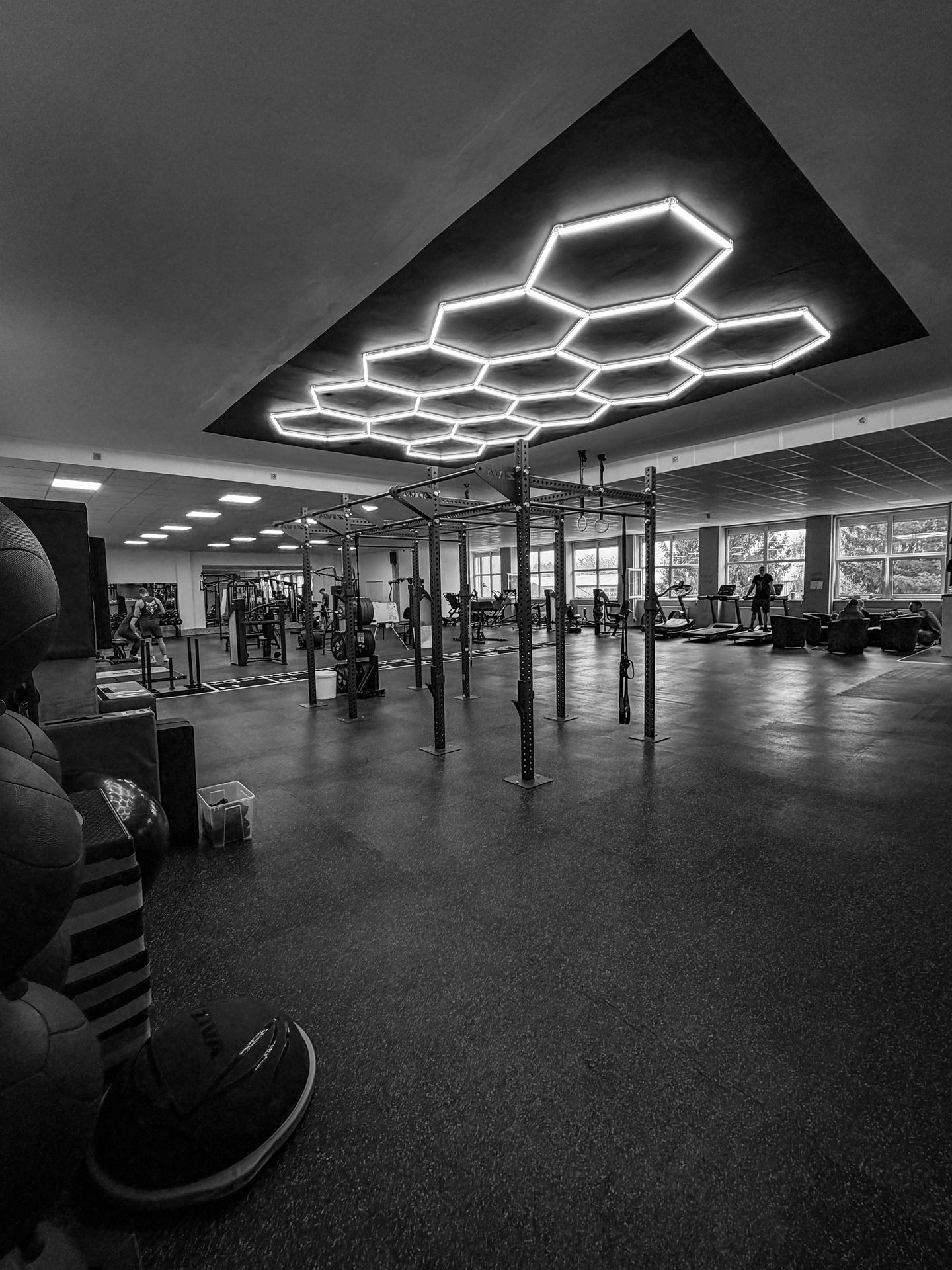 Obří ocelový rig se čtyřmi squat racky a hrazdami pro gymnastiku a kalisteniku v prostoru s vysokými stropy
